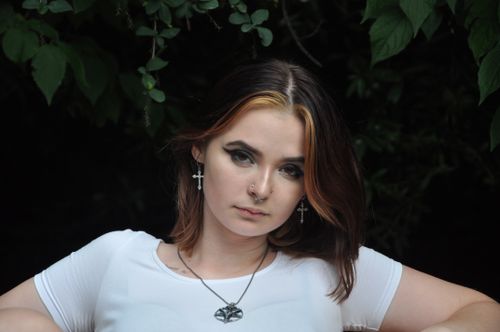 Free Thoughtful portrait of a young woman with striking makeup in an outdoor natural setting. Stock Photo