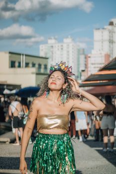 Woman in colorful festival attire enjoying a sunny outdoor event.