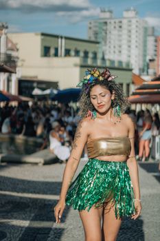 Woman in a vibrant costume enjoys a festive outdoor celebration with a crowd in the background.