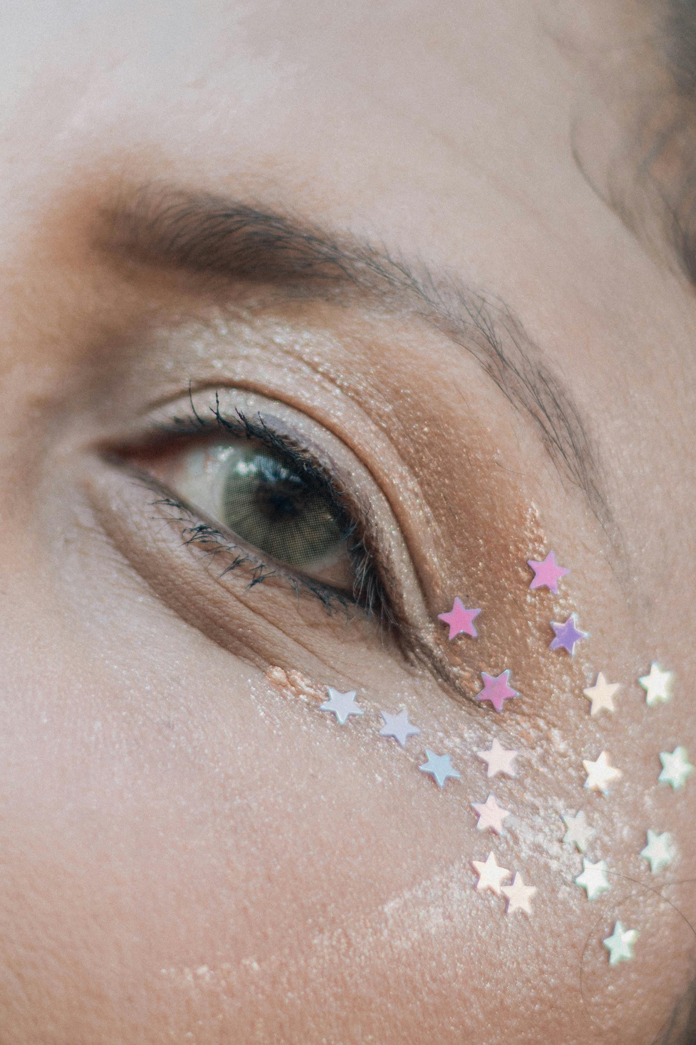 A detailed close-up of an eye adorned with star-shaped glitter for a creative makeup look.
