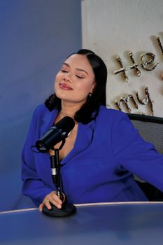 Woman enjoying a moment in a podcast studio, microphone in hand, serene ambiance.