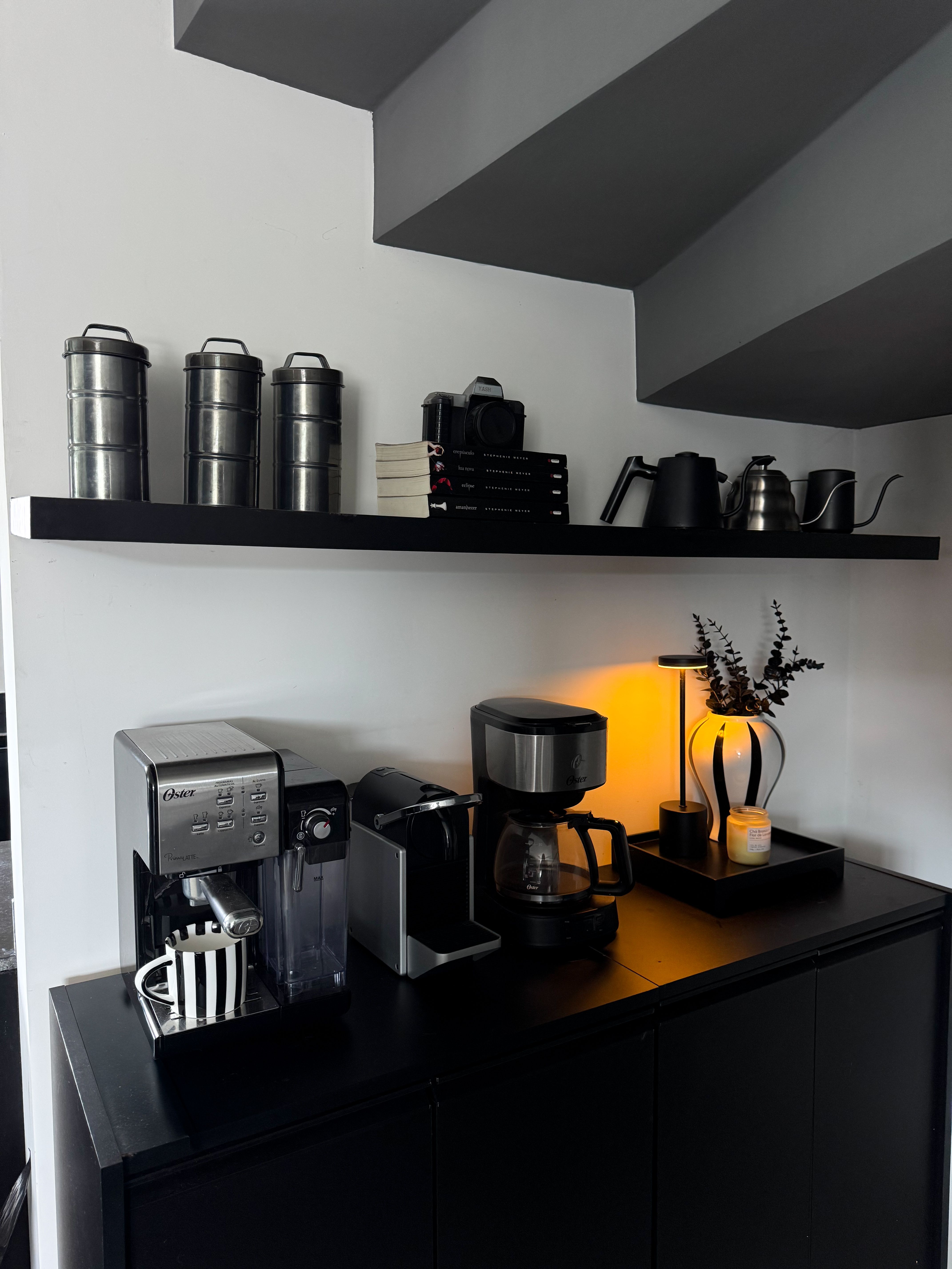 Backlit floating shelves holding coffee mugs and accessories above a home coffee bar