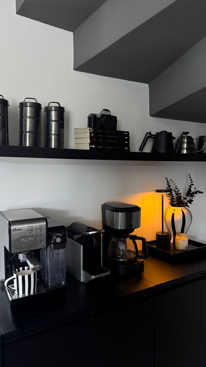 Backlit floating shelves holding coffee mugs and accessories above a home coffee bar