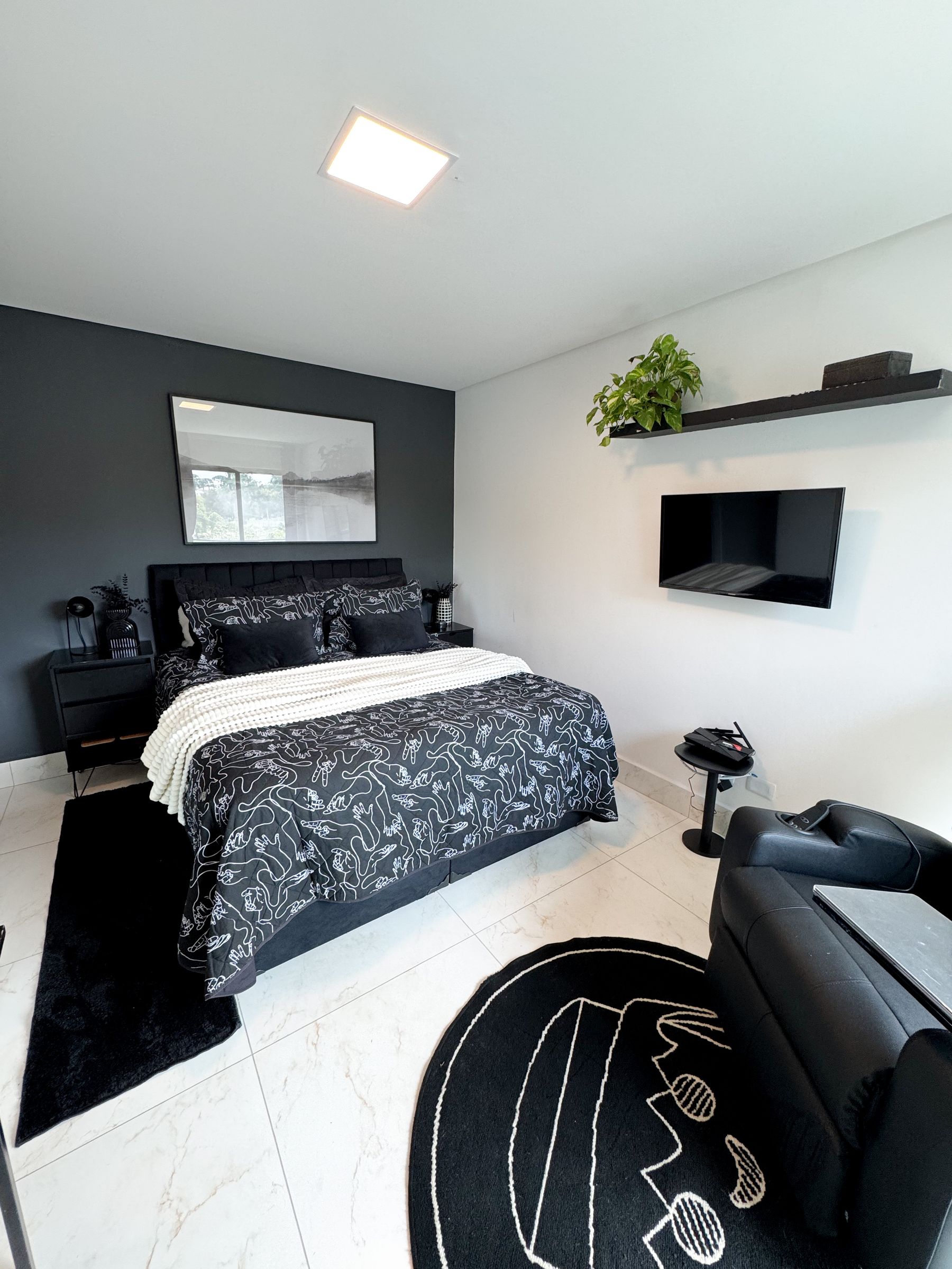 Minimal pale bedroom with black bed frame, dark lamp and restrained neutral bedding