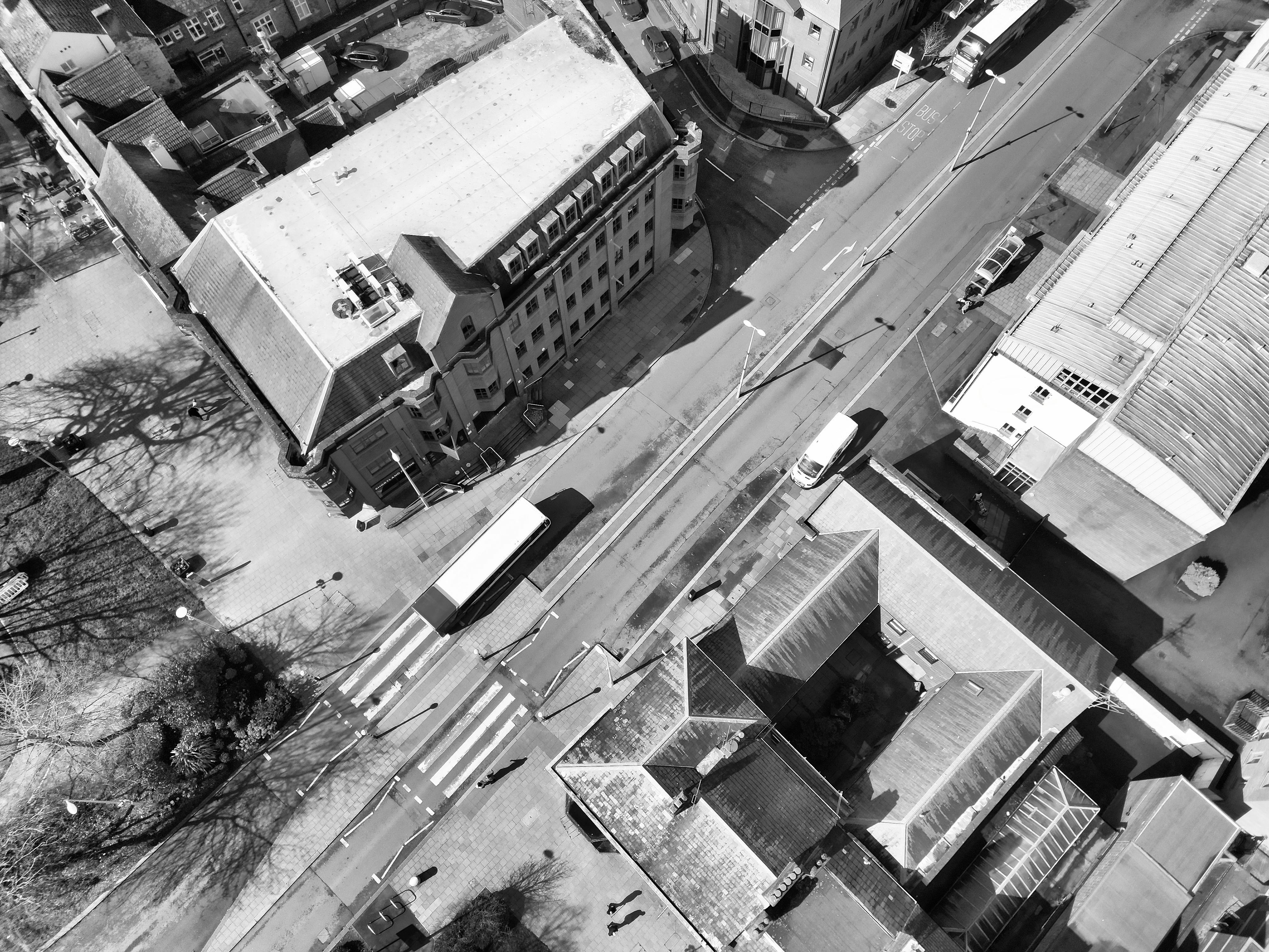 Zadarmo Monochromatický letecký pohľad na mestskú ulicu s budovami, vozidlami a priechodmi pre chodcov. Fotka z fotobanky