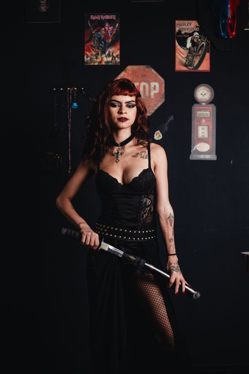 Free A woman with a gothic style holds a baseball bat in a dark, vintage-themed room. Stock Photo
