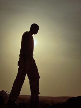 Silhouette of a man walking during sunrise, creating a calm and introspective mood.