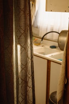Warm light filters through a curtain revealing a cozy kitchen sink scene in Valparaíso, Chile.