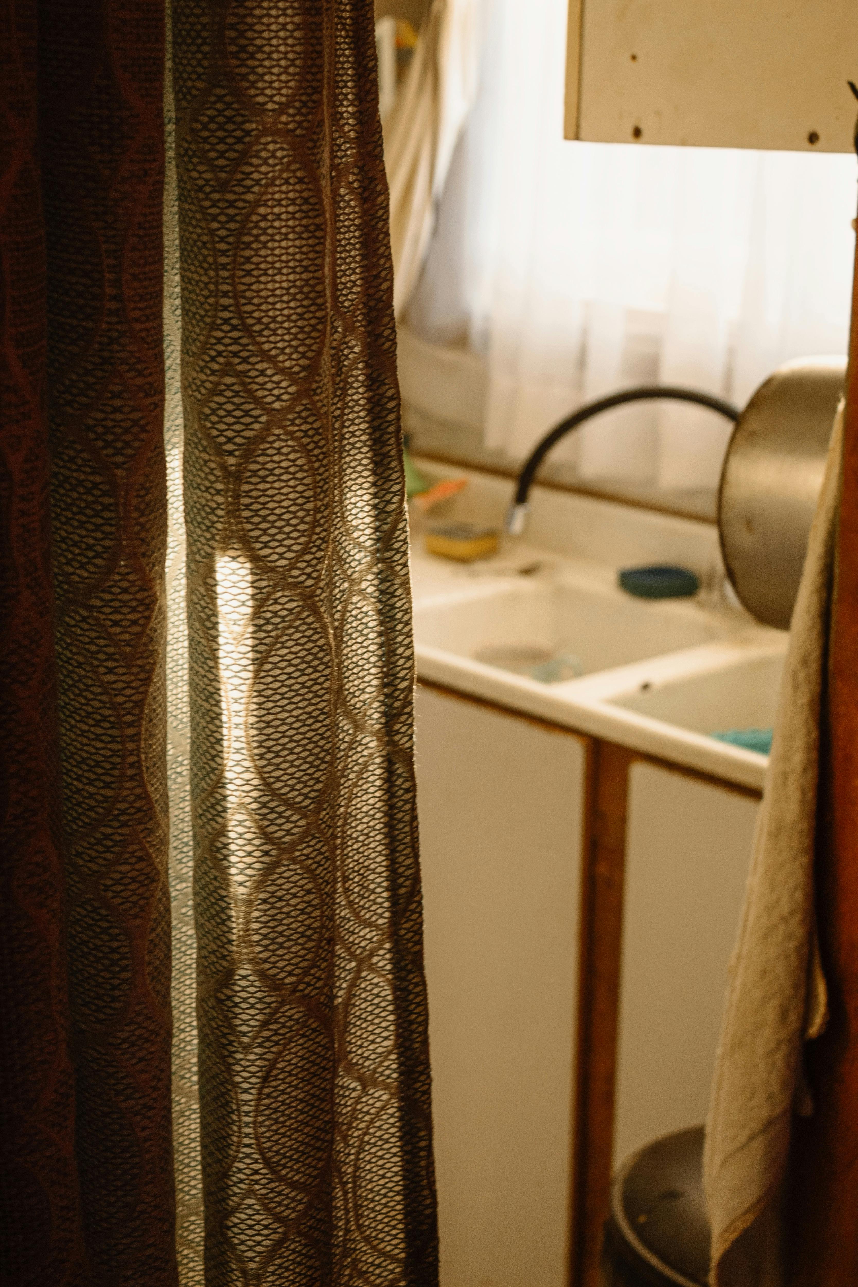Free Warm light filters through a curtain revealing a cozy kitchen sink scene in Valparaíso, Chile. Stock Photo