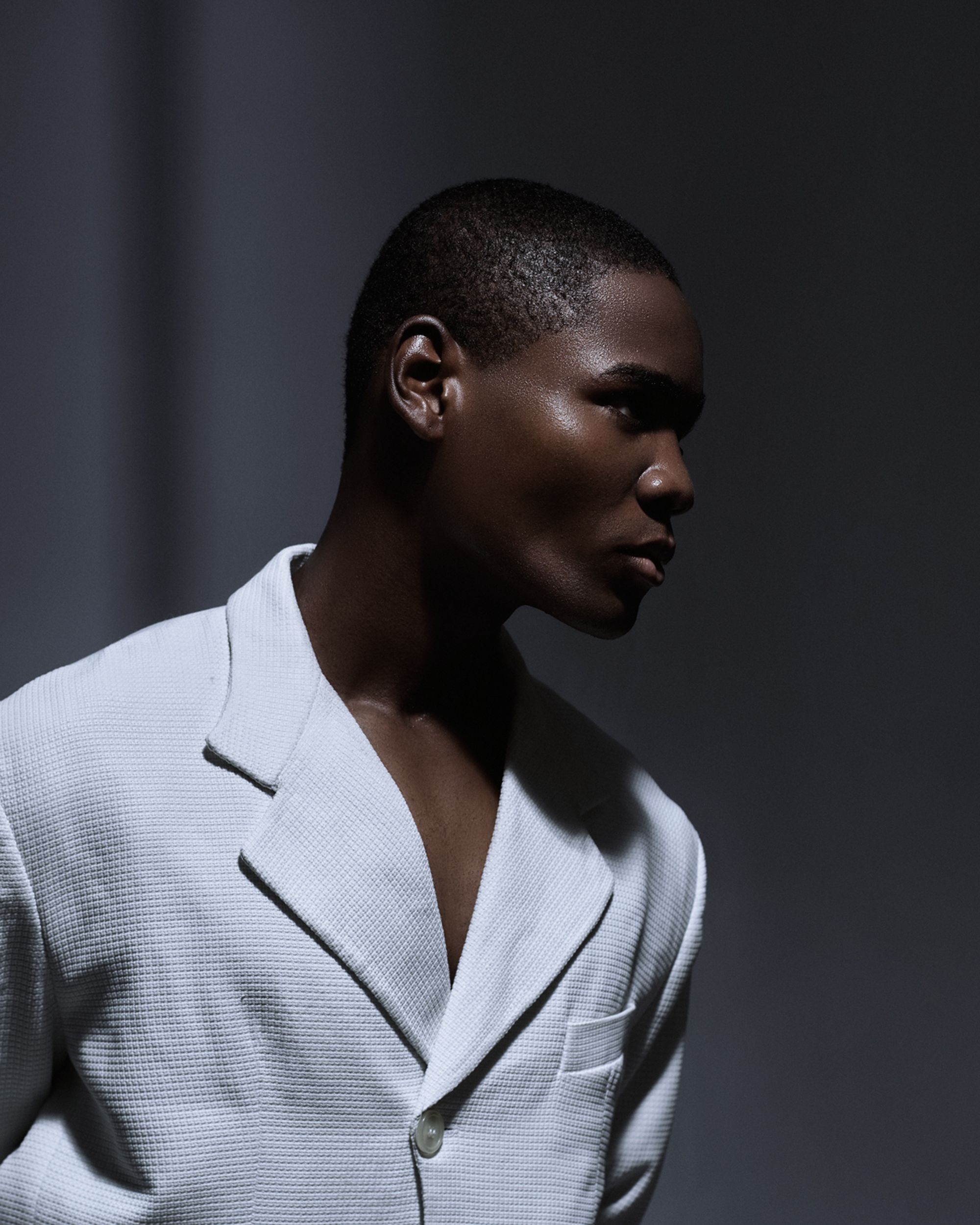 Sophisticated portrait featuring a person in a white suit with dramatic lighting, conveying elegance and style.