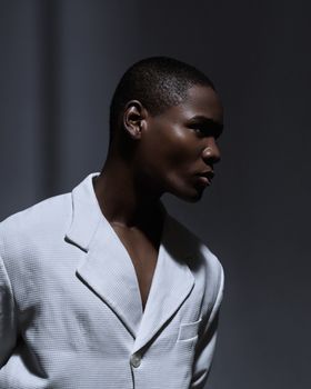 Sophisticated portrait featuring a person in a white suit with dramatic lighting, conveying elegance and style.
