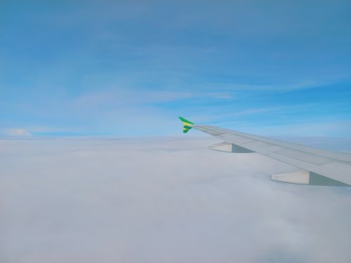 Free Aerial view of an airplane wing flying over a sea of clouds under a clear blue sky. Stock Photo