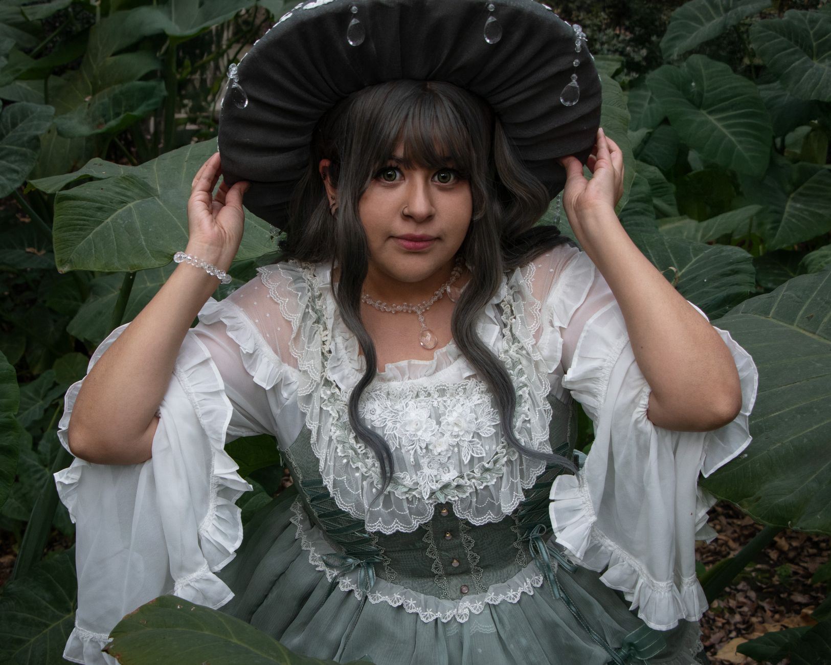 A woman in a vintage green dress poses amid lush greenery in Mexico City's botanical garden.