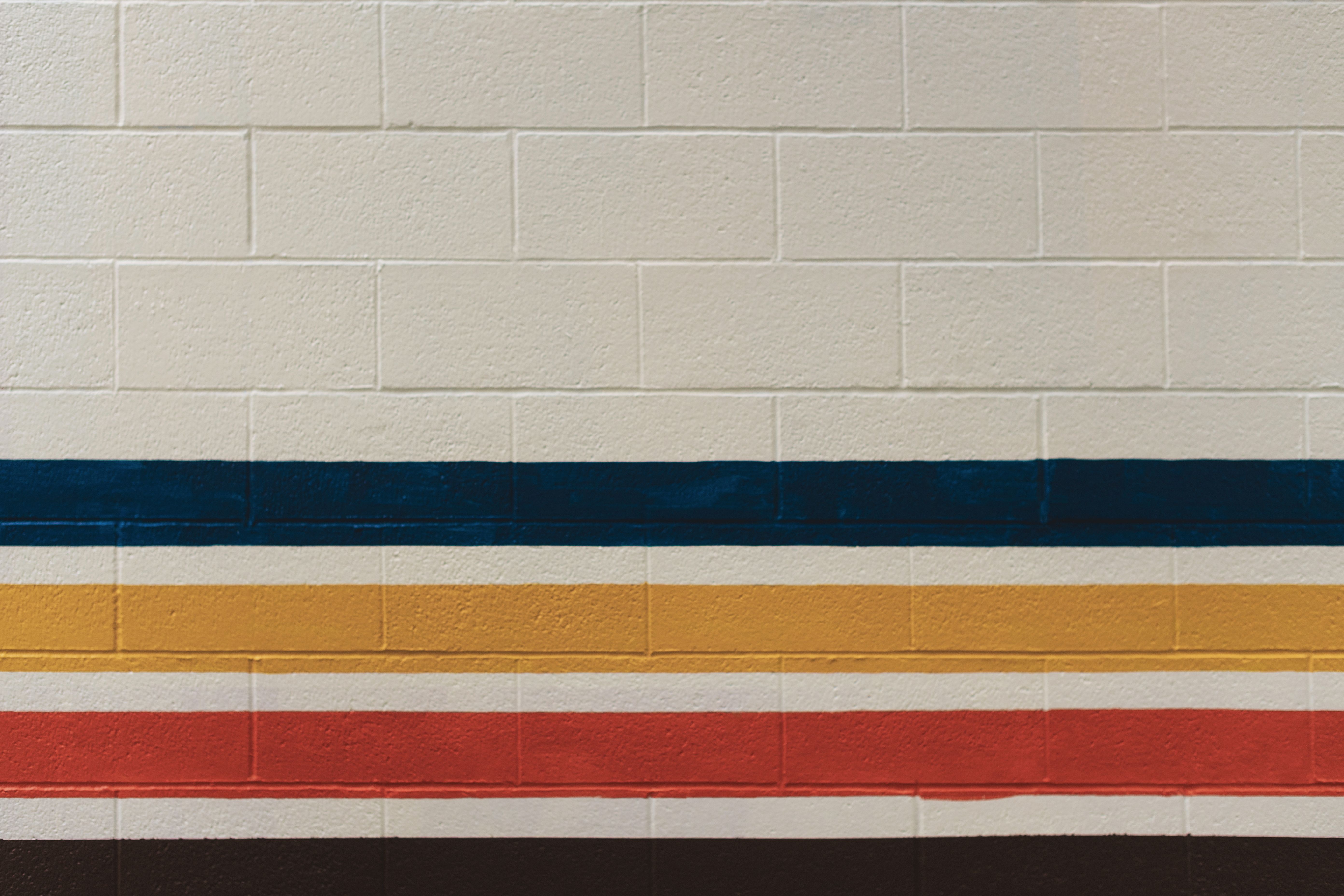 Vibrant brick wall displaying colorful horizontal stripes for artistic and urban design.