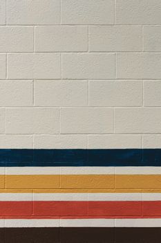 Minimalist brick wall featuring colorful horizontal stripes, ideal for background and texture.