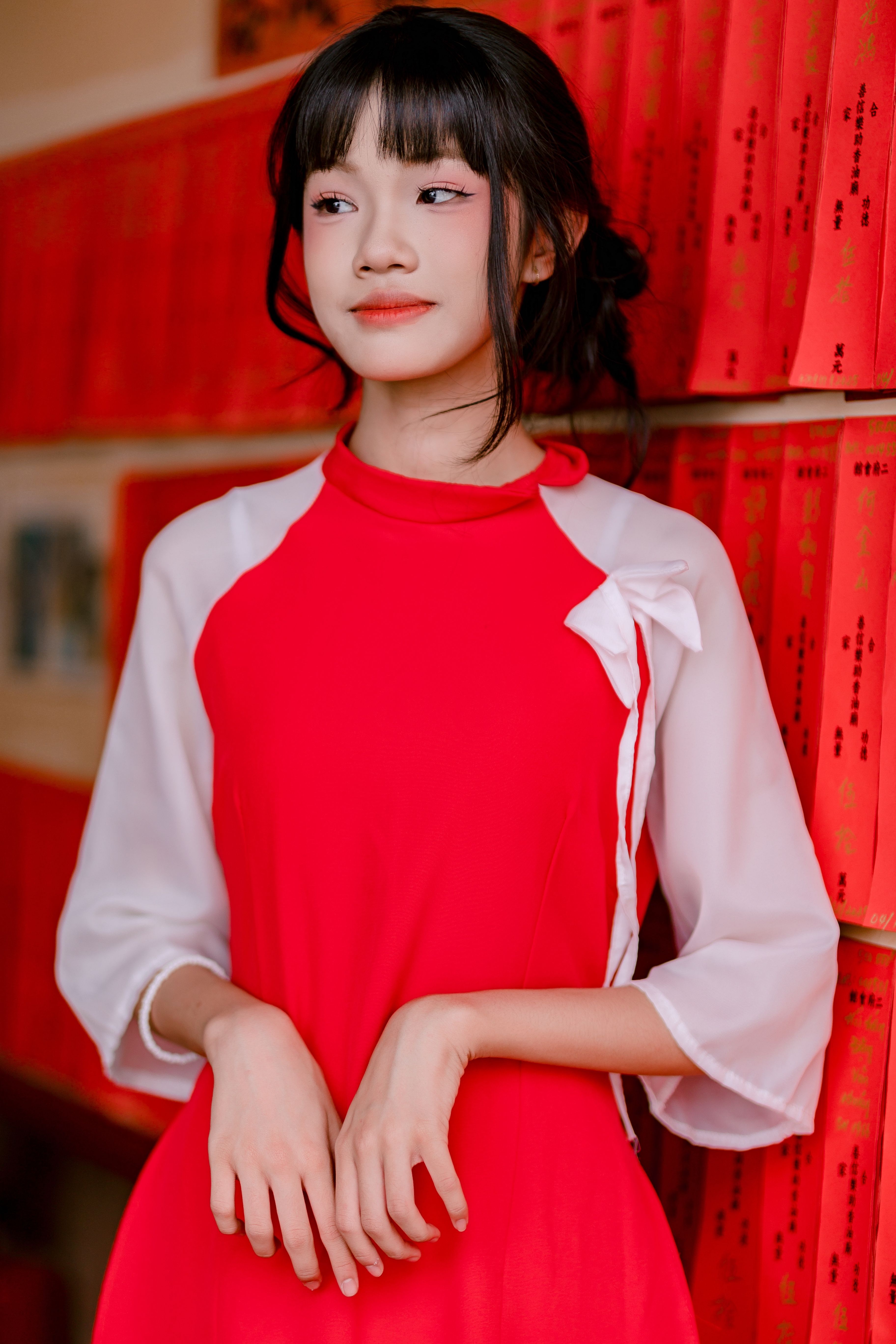 Charming young woman in a red traditional dress posing indoors with a serene expression.