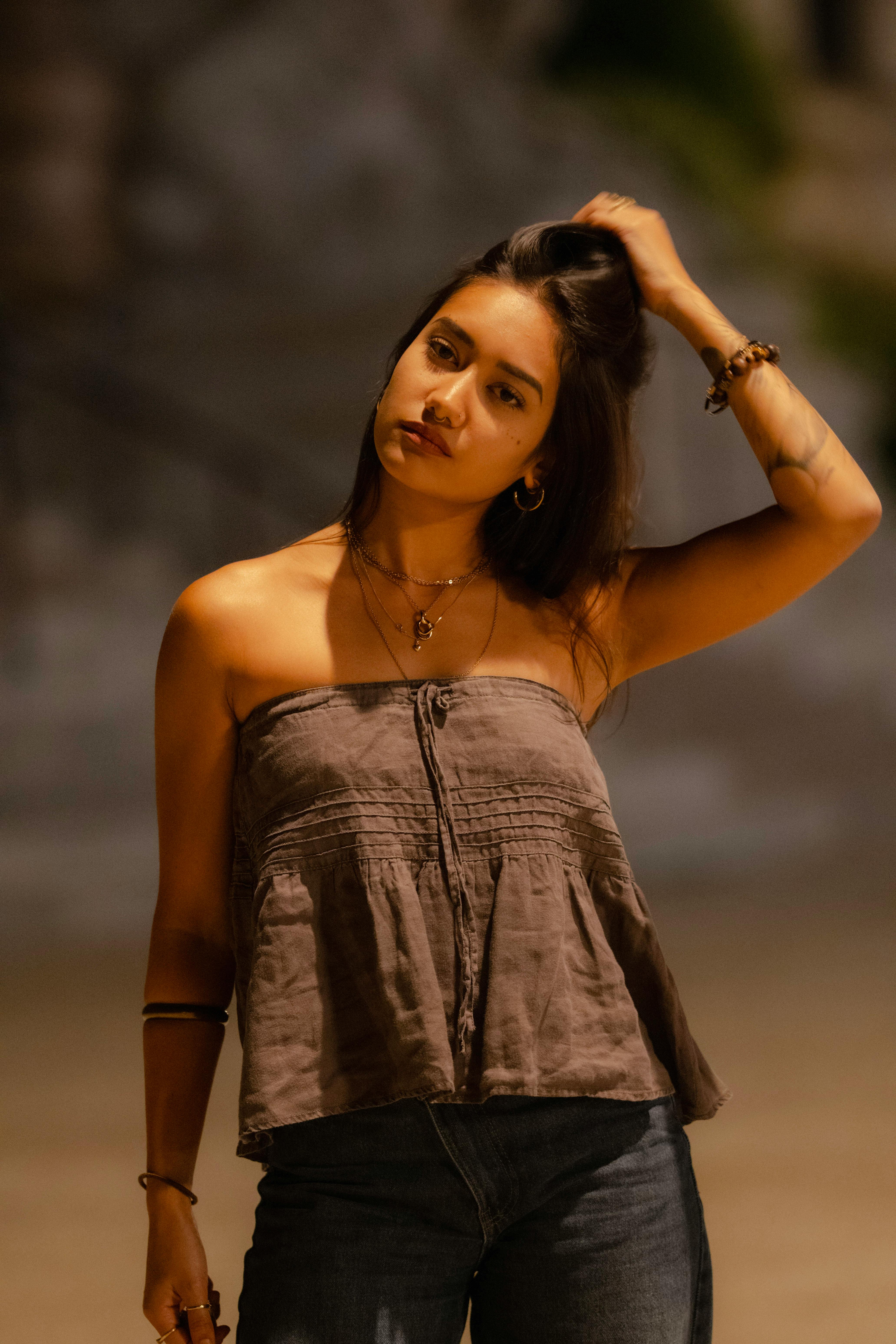 Безкоштовне Захопливий портрет жінки з темним волоссям, яка вночі розслаблено позує на вулиці. стокове фото