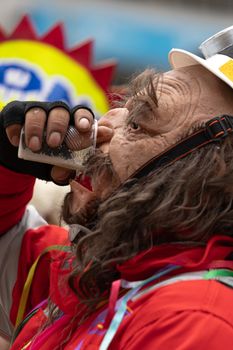 A man in vibrant costume enjoys a drink during a festive celebration in Tarma, Peru.