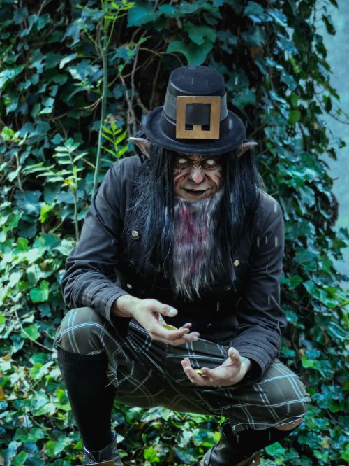 Free A mysterious character dressed as an elf in a lush, overgrown garden creates a haunting atmosphere. Stock Photo