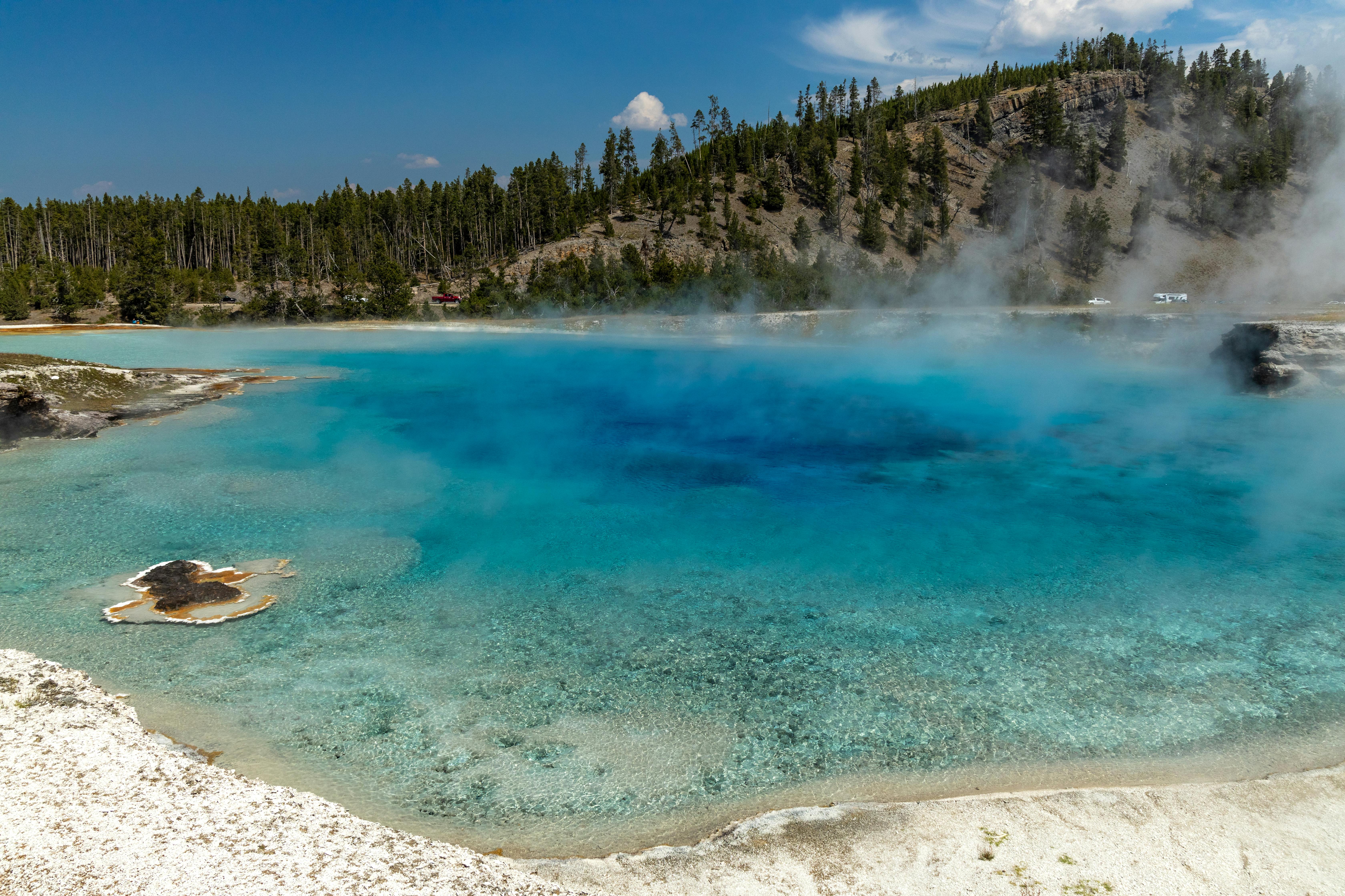 Capture of a vibrant blue hot spring surrounded by nature in Yellowstone National Park, Wyoming.