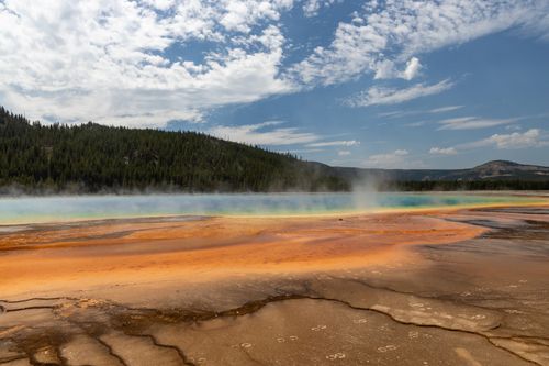 Free Vibrant hot spring in Yellowstone National Park with colorful mineral layers under a clear summer sky. Stock Photo