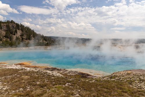 Free A breathtaking view of a steaming hot spring surrounded by nature in Yellowstone National Park. Stock Photo