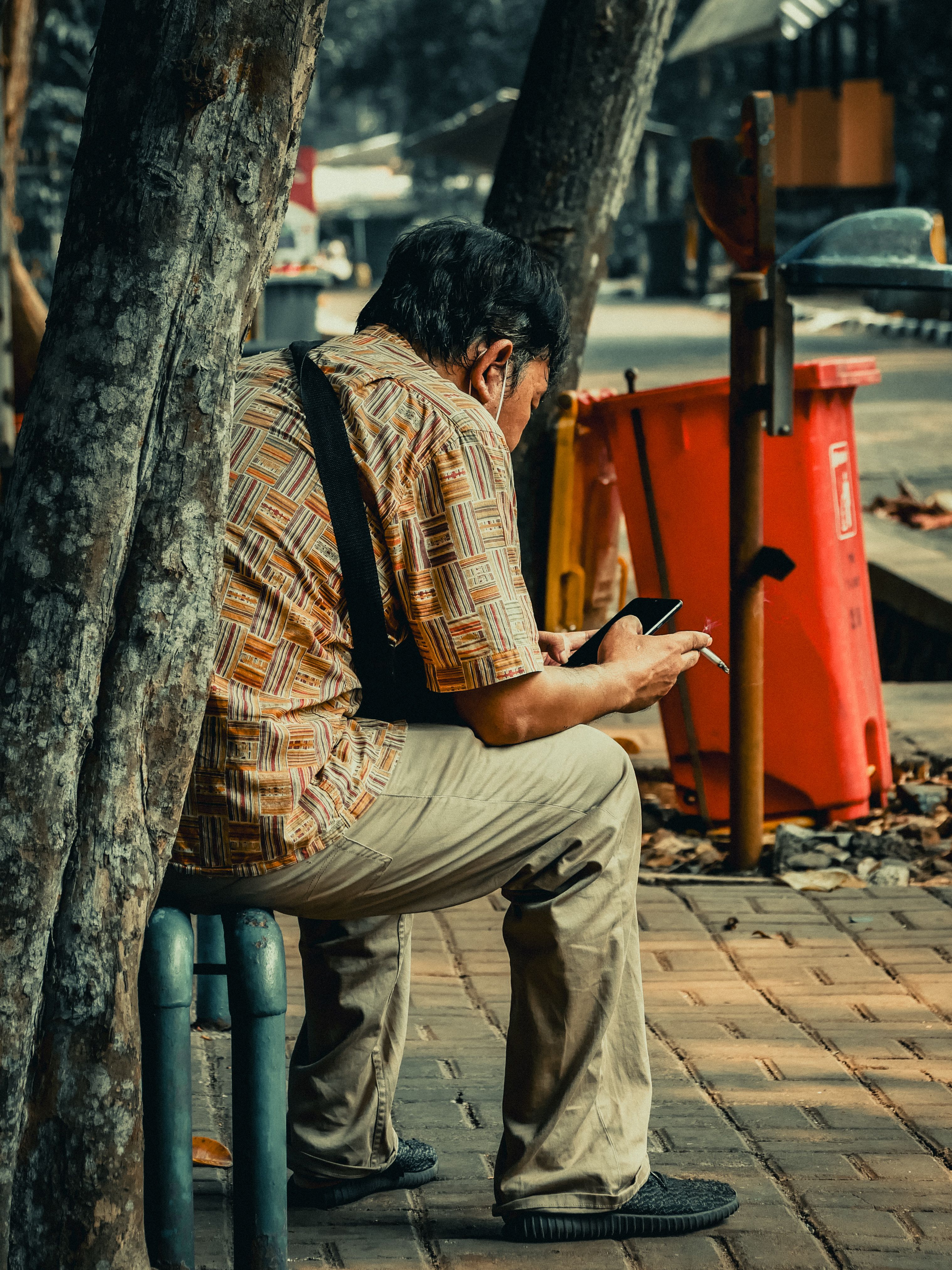 Man Sitting Outdoors Using Smartphone in Urban Setting