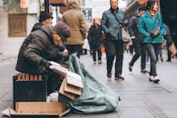 在繁忙的北京街头，一位老人坐在长凳上，周围是行人和城市生活的景象