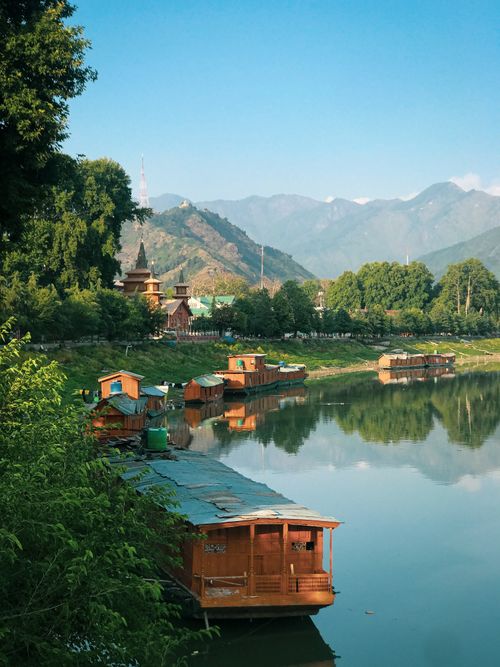 Free Peaceful houseboats on a calm lake surrounded by trees and mountains under a clear blue sky. Stock Photo