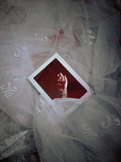 Free A creative display of a hand reflected in a mirror, surrounded by delicate fabric. Stock Photo