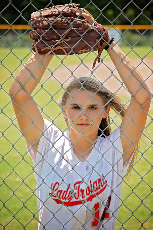 무료 울타리 앞 야구 미트와 흰색 크루 넥 티셔츠에 여자 스톡 사진