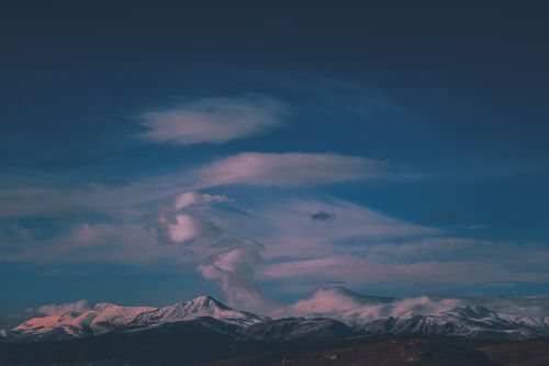 Free Snow-capped mountains under a dramatic evening sky with pink clouds. Stock Photo