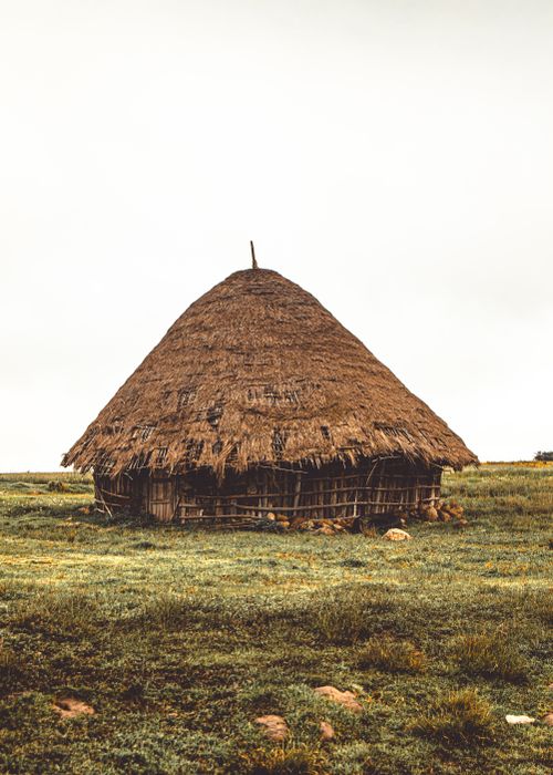 Free A traditional grass-roofed hut located in the scenic Ethiopian countryside, embodying cultural heritage. Stock Photo