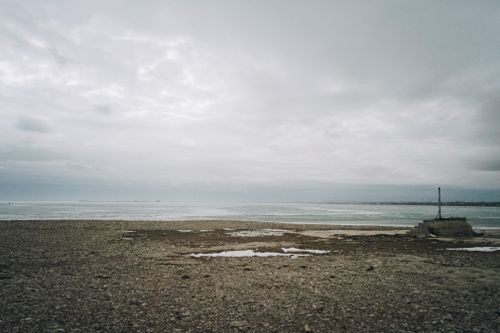 Free A tranquil pebble beach under a cloudy sky at a lake in Konaev, Kazakhstan. Stock Photo