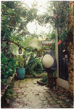Enchanting garden path with lush greenery and iconic Totoro statue decor.