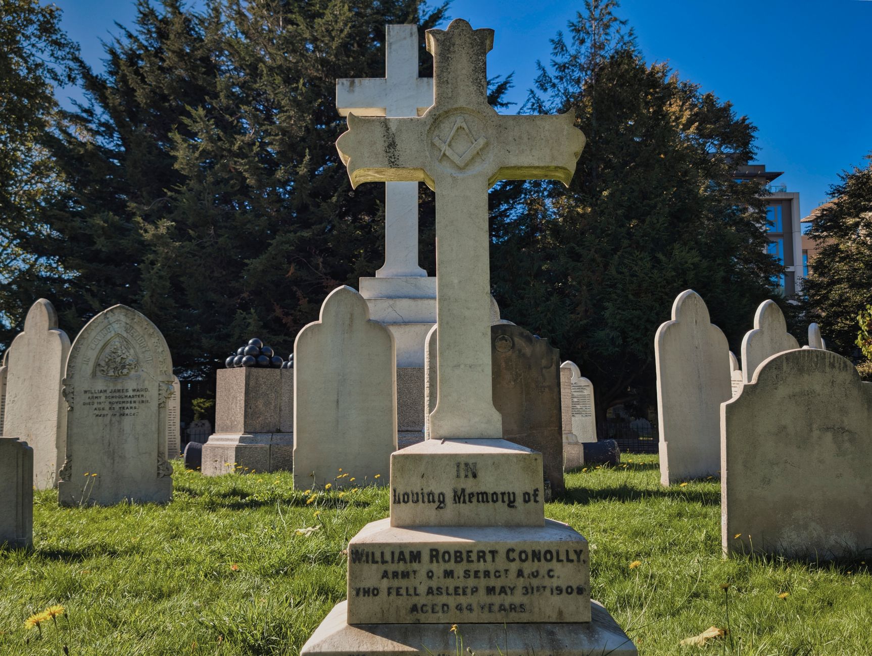 A serene view of gravestones in a historic London cemetery on a sunny day.