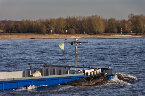 Free A cargo ship navigating a serene river, highlighting transportation and maritime logistics. Stock Photo