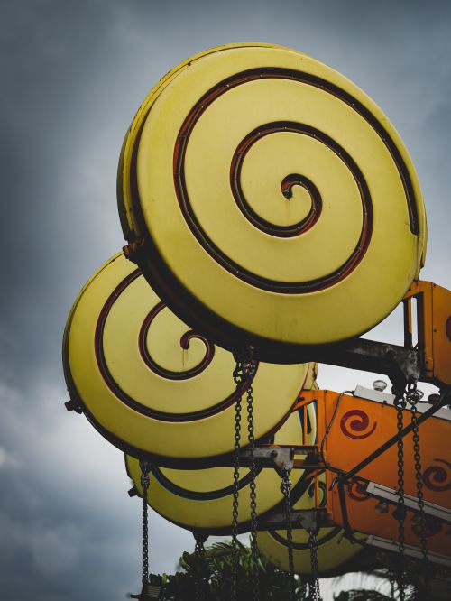 Free Bright yellow carnival ride against a dramatic stormy sky, capturing the essence of fun and thrill. Stock Photo