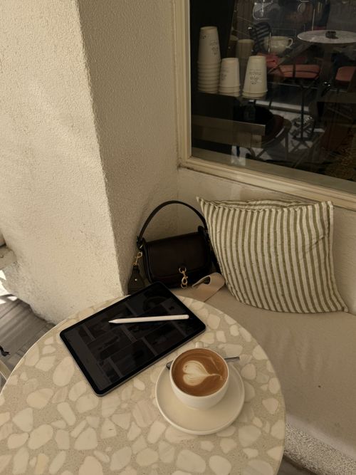 Free Stylish café setting featuring a tablet, latte art, and a handbag, perfect for mobile work. Stock Photo