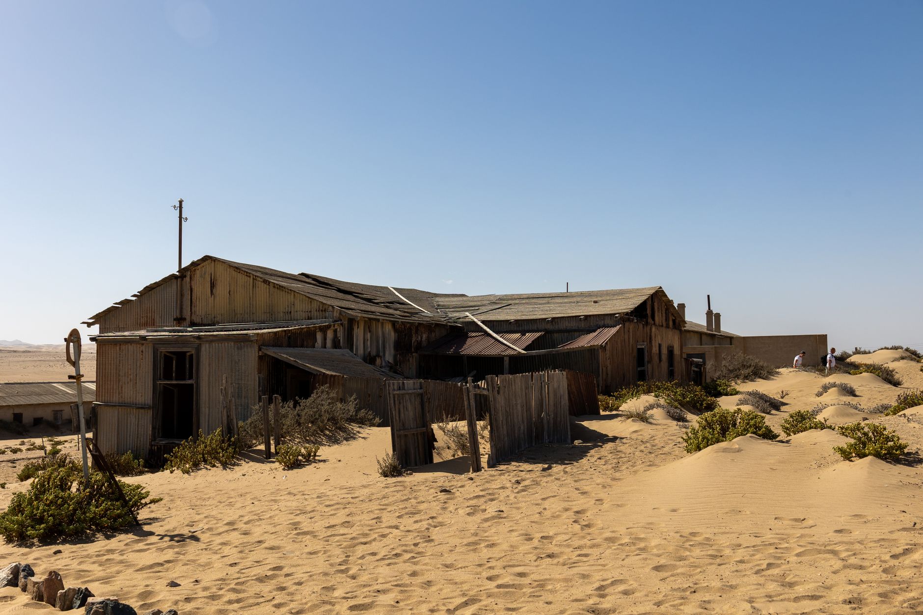Rustic abandoned building in Namibia's desert landscape, surrounded by sand dunes.