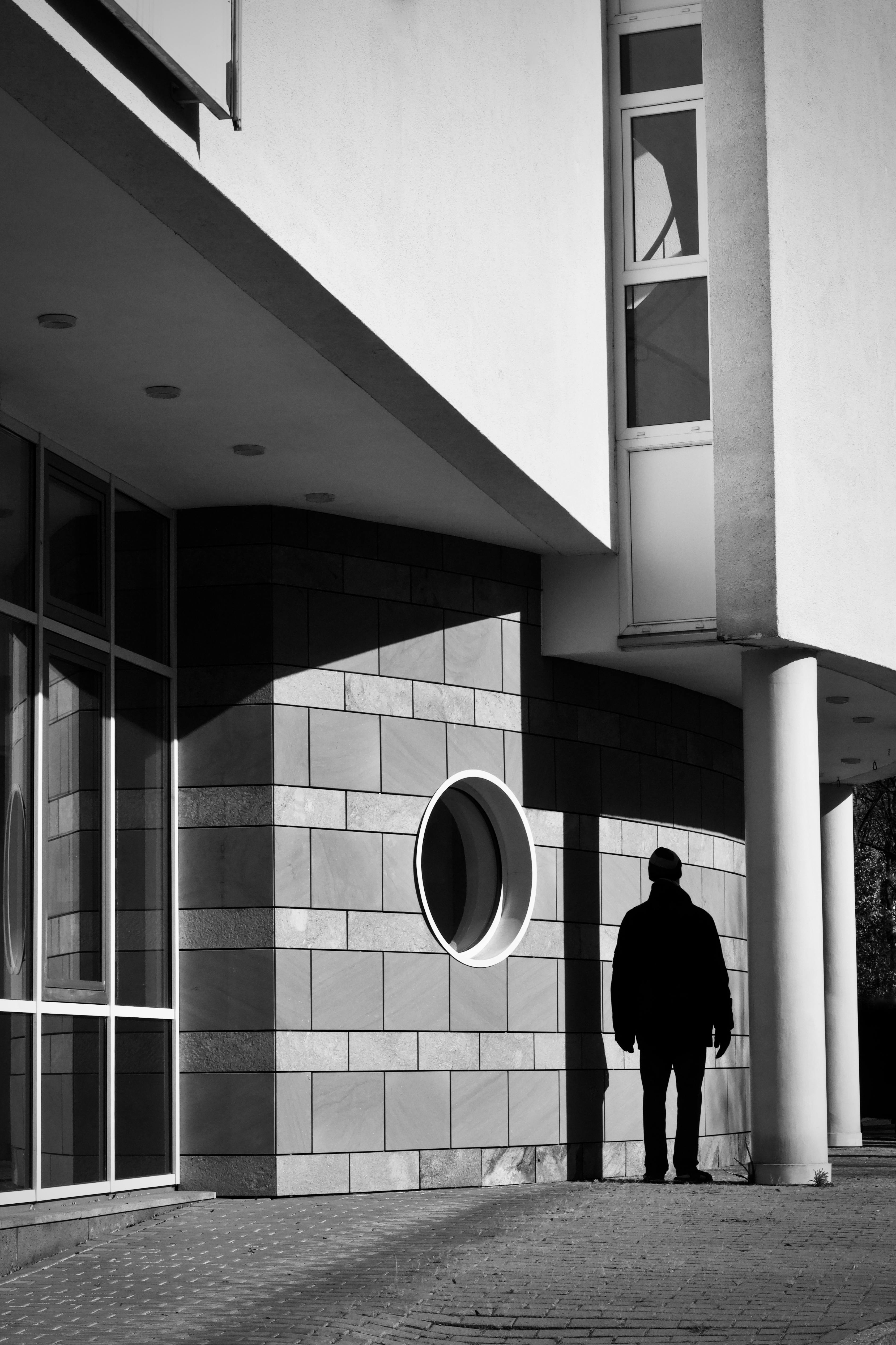 Gratis Foto in bianco e nero di una persona in controluce rispetto all'esterno di un edificio moderno. Foto a disposizione