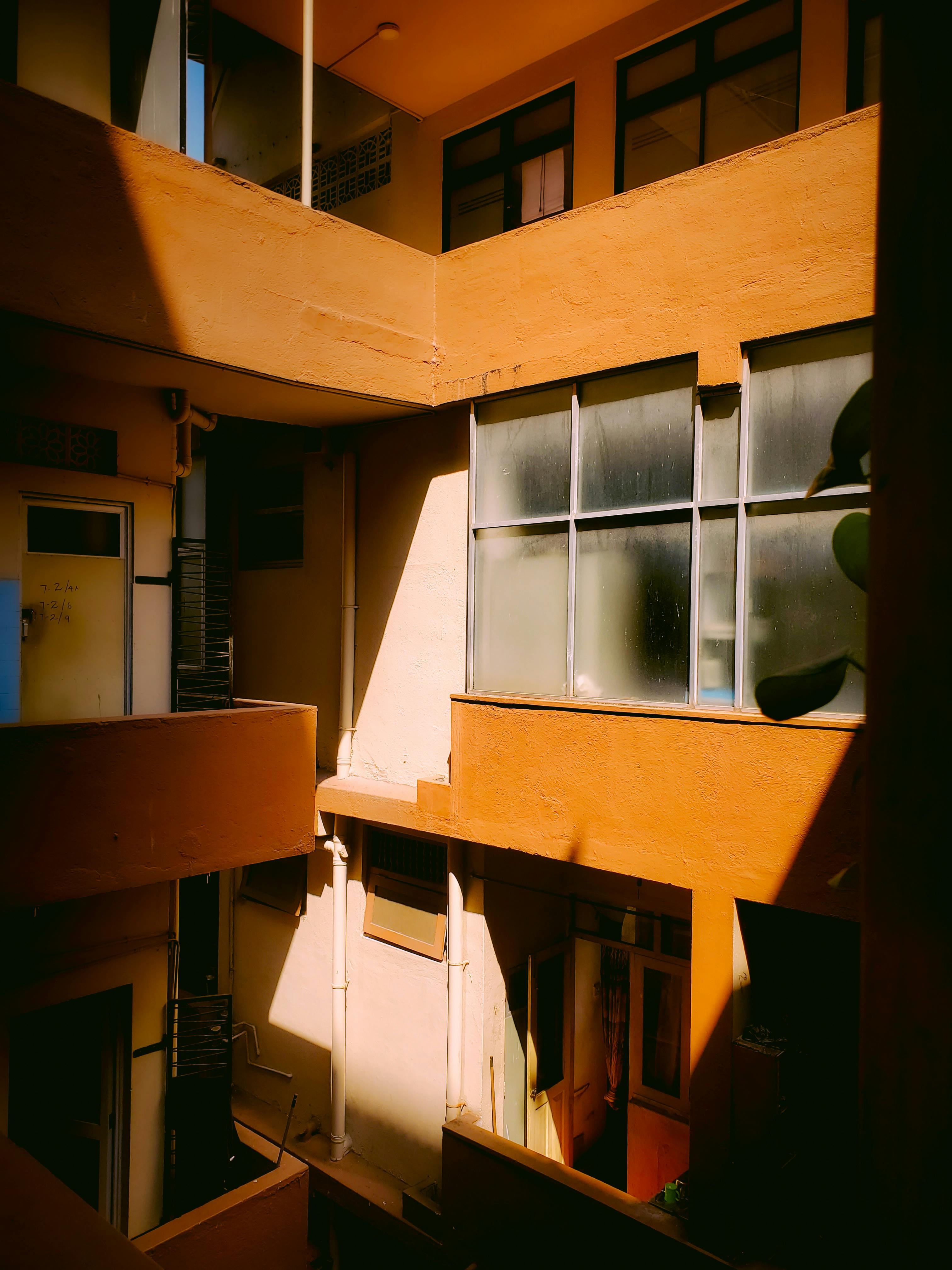 Kostenlos Warmes Sonnenlicht wirft Schatten in das Innere eines modernen Apartmentgebäudes und schafft so eine künstlerische und gemütliche Atmosphäre. Stock-Foto