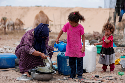 Free A woman and children gather water in a desert area of Gaza, highlighting daily life. Stock Photo