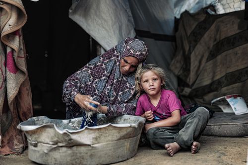 Free A cultural scene depicting a mother and child in a tent, emphasizing resilience in Gaza. Stock Photo
