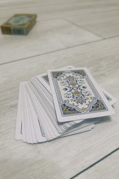 A shuffled stack of playing cards lies on a light wooden floor, perfect for game night themes.