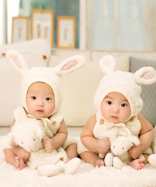 무료 흰색 머리 장식을 입고 흰색 봉제 장난감을 들고있는 2 명의 아기 스톡 사진
