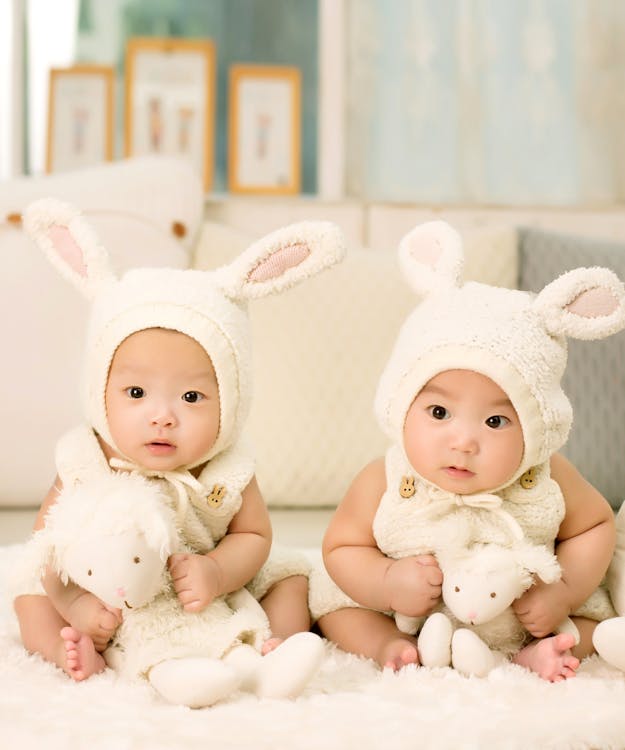 Free 2 Babies Wearing White Headdress White Holding White Plush Toys Stock Photo