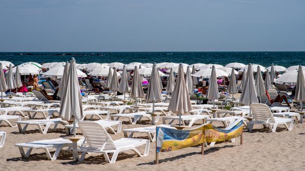 A bustling Croatian beach with sun umbrellas and lounge chairs, perfect for vacation relaxation.