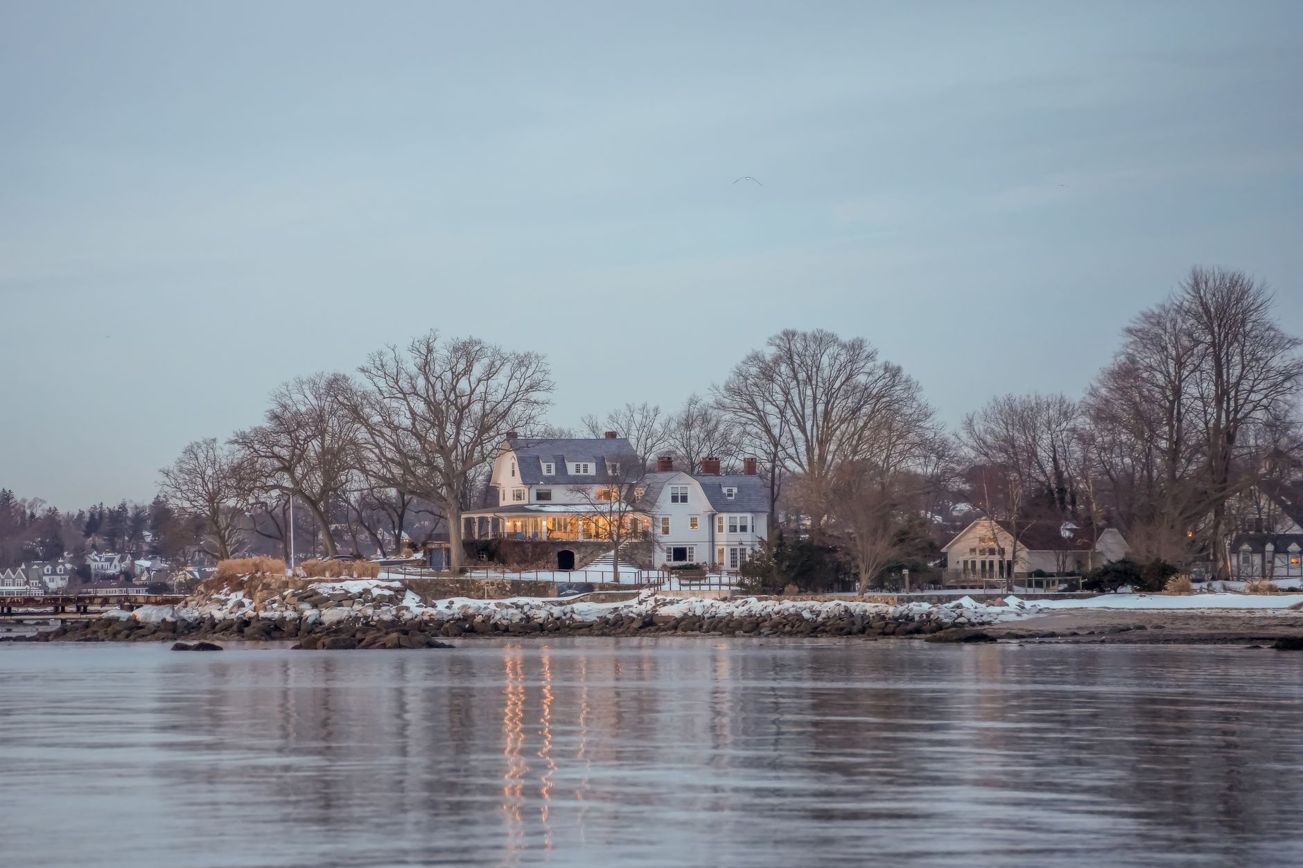 Scenic view of elegant coastal home reflecting on water at dusk in Stamford, Connecticut.