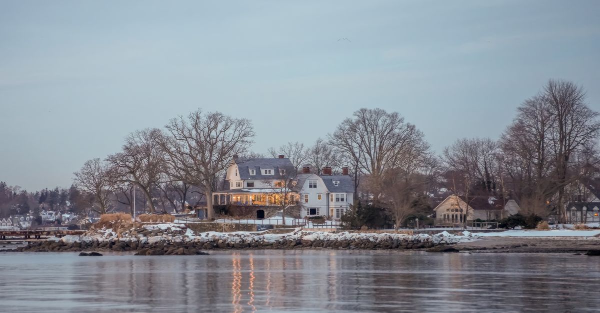 Scenic view of elegant coastal home reflecting on water at dusk in Stamford, Connecticut.